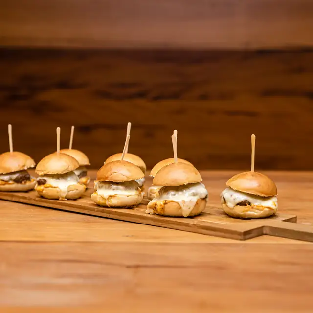Mini burgers no palito sobre tábua de madeira